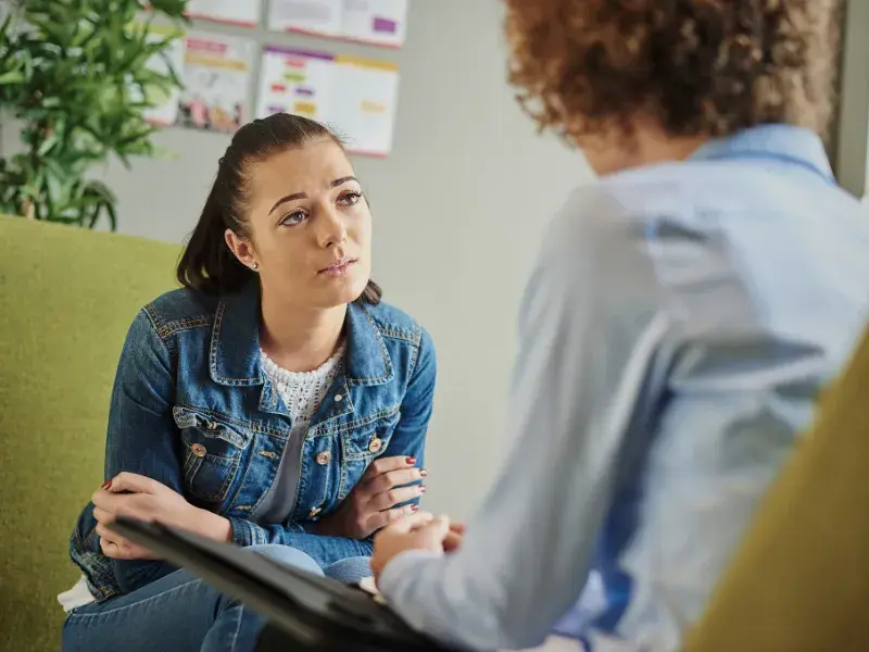Individuals sitting on a chair in a counseling setting. 